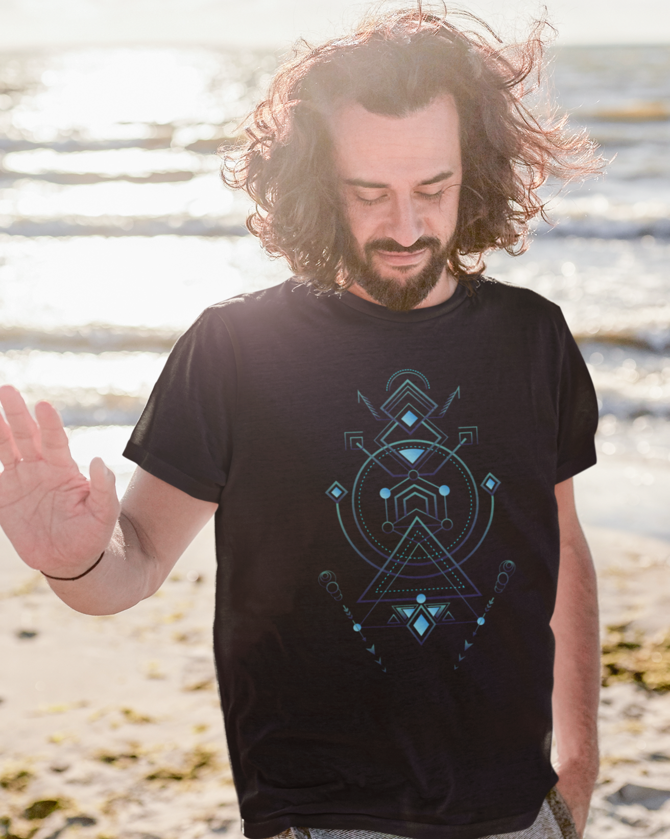 Man wearing a black t-shirt with a geometric design on a beach
